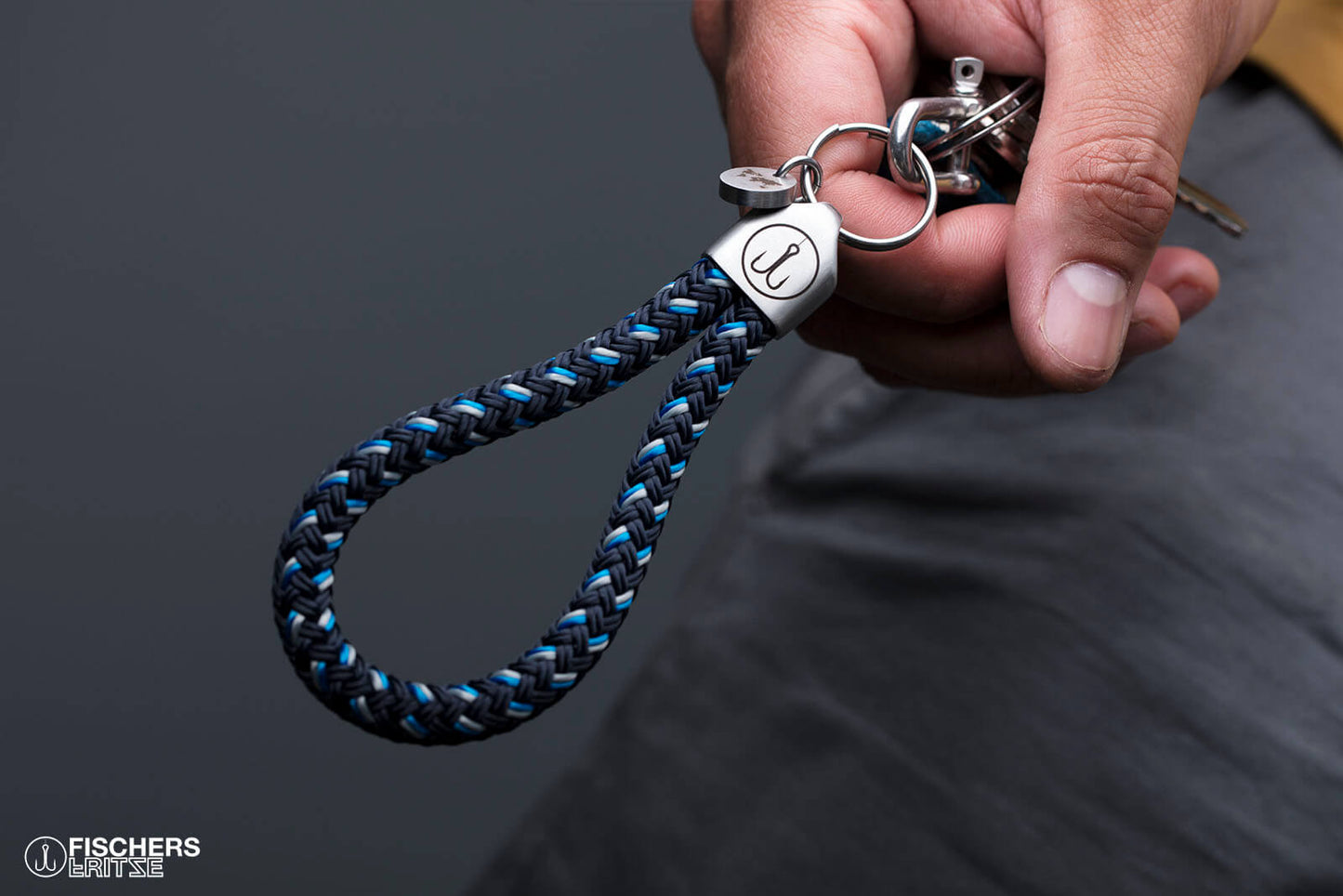 Hand haelt Schluesselanhaenger Segeltau marineblau blau grau, Edelstahlfassung mit Gravur sichtbar