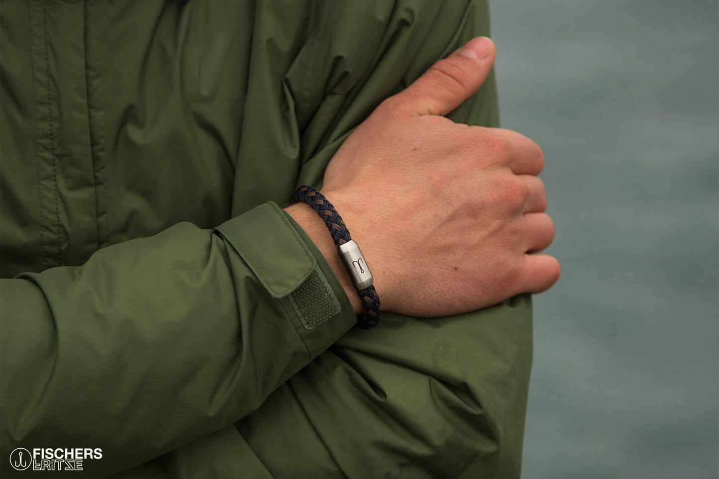 Gekreuzte Arme, umgelegtes Armband marineblau braun aus Segeltau mit Angelhaken Gravur von Fischers Fritze