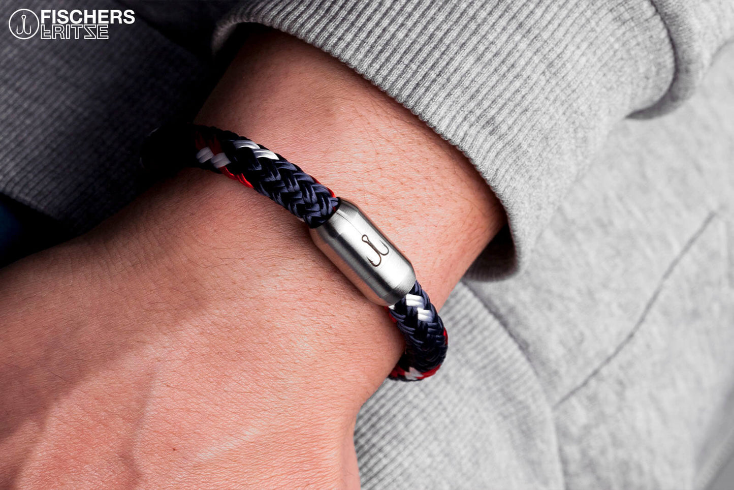 Um Handgelenk gelegtes, maritimes Fischers Fritze-Armband aus Tau, Makrele marineblau rot weiss, Edelstahl Gravur