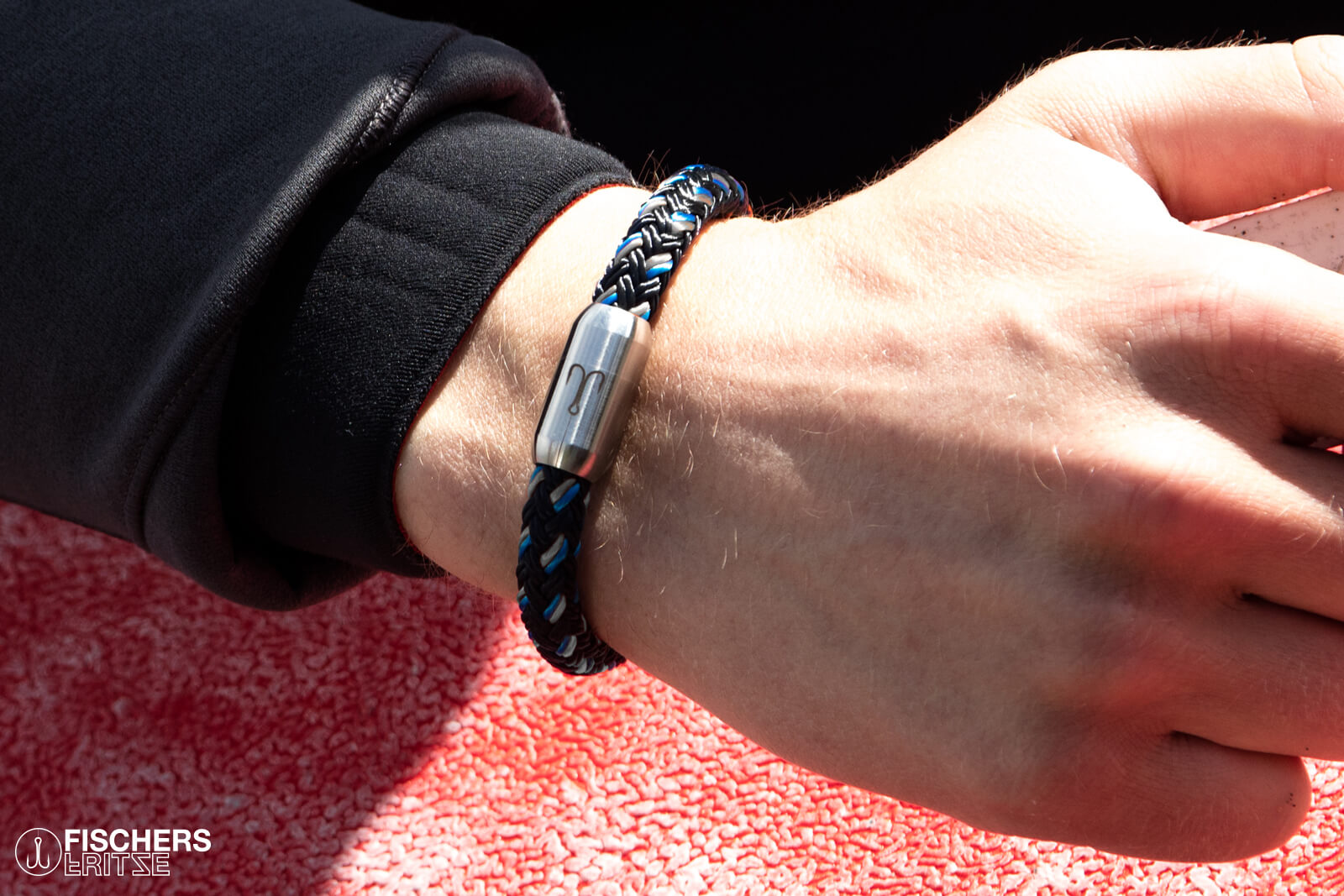 Fischers Fritze-Armband aus Segeltau, Makrele marineblau stahlblau silbergrau am Handgelenk eines Wellensurfer